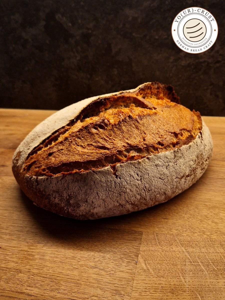 Same Day Bread — a whole sourdough loaf with a golden, floury crust on a wooden board